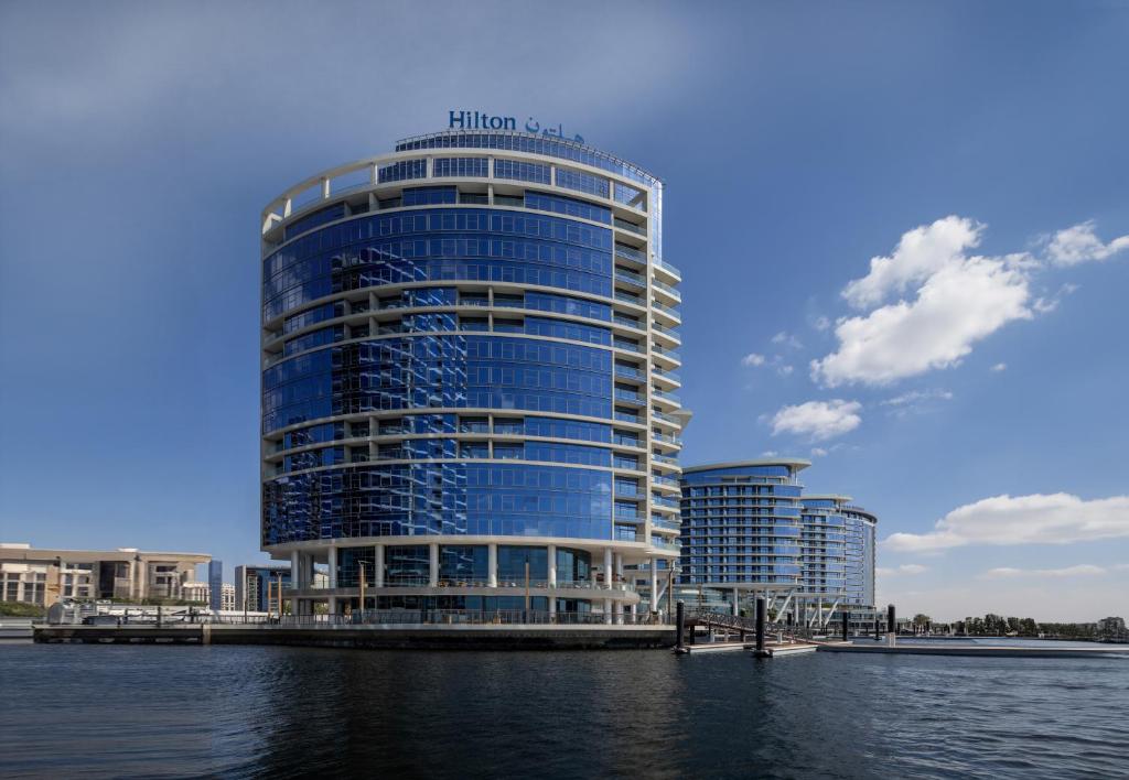 迪拜Hilton Dubai Creek Hotel & Residences的靠近水体的蓝色高楼