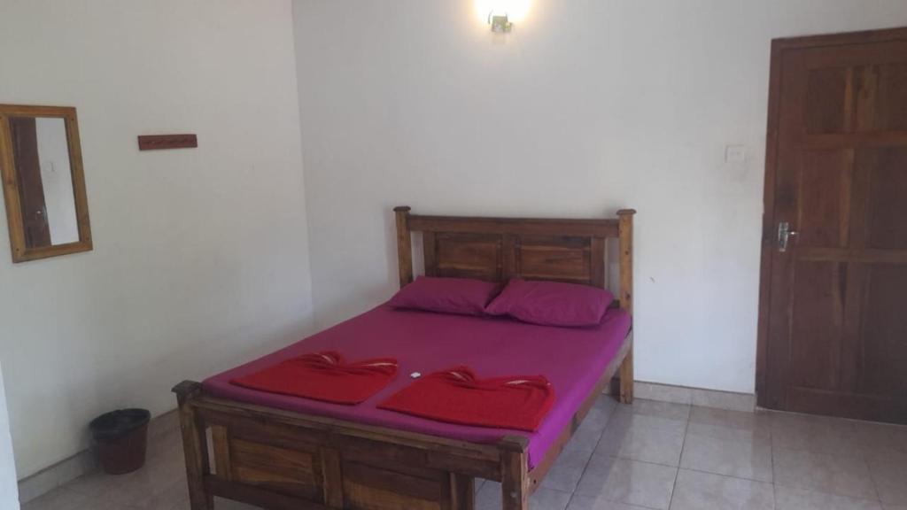 康提Suriya Villa的一间卧室配有一张带紫色床单和红色枕头的床。