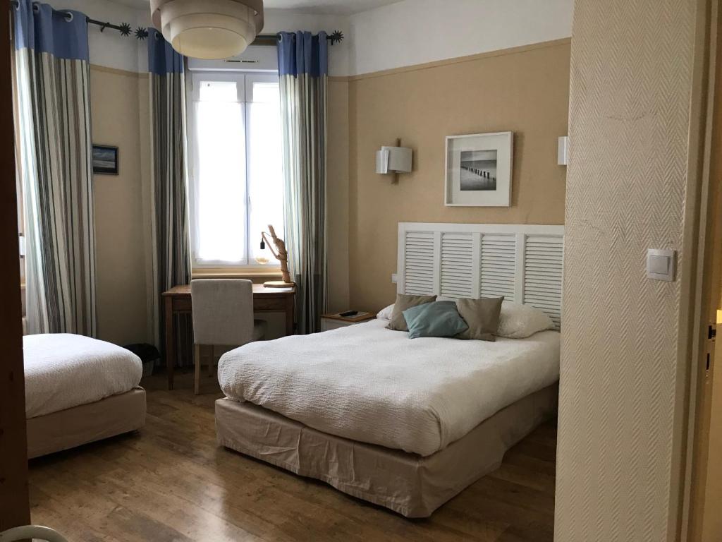 滨海贝尔克Logis Hôtel & Restaurant "Au Gré du Vent"的一间卧室设有两张床、一张桌子和一个窗口