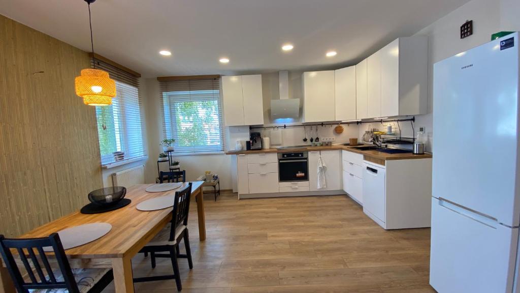 考纳斯Japandi apartamentai的厨房配有白色橱柜和木桌