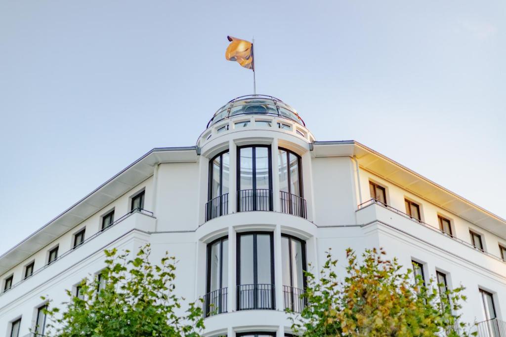 宾茨A-ROSA Collection Hotel Ceres am Meer的顶部有旗帜的白色建筑
