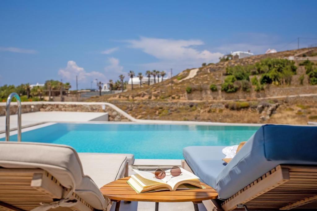 米克诺斯城Aqua Breeze Seaview Pool Suites Mykonos的一个带椅子和桌子的游泳池,