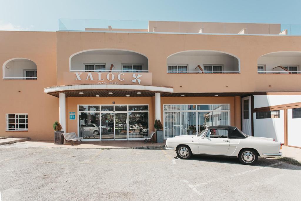 蓬塔普里马Hotel Xaloc Playa的停在大楼前的白色汽车