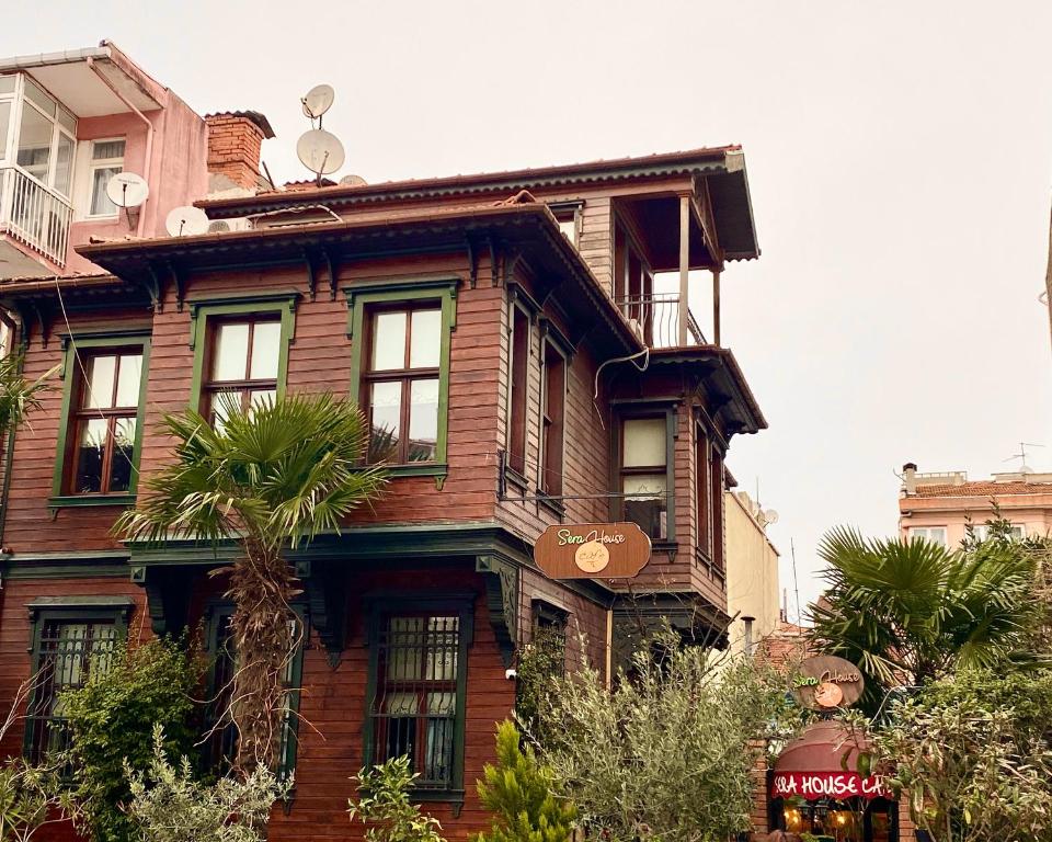 伊斯坦布尔塞拉之家奥斯曼套房酒店的一座古老的木房子,前面有一棵棕榈树