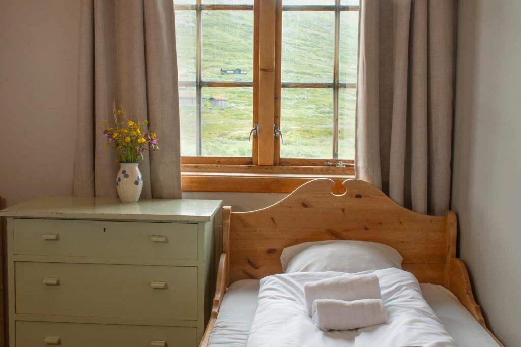 EidsbugardenTyinholmen Høyfjellsstuer的一间卧室配有带梳妆台和窗户的床。