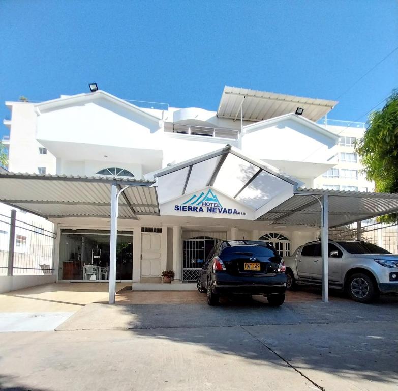 巴耶杜帕尔Hotel Sierra Nevada B&B SAS的一座白色的建筑,两辆车停在停车场