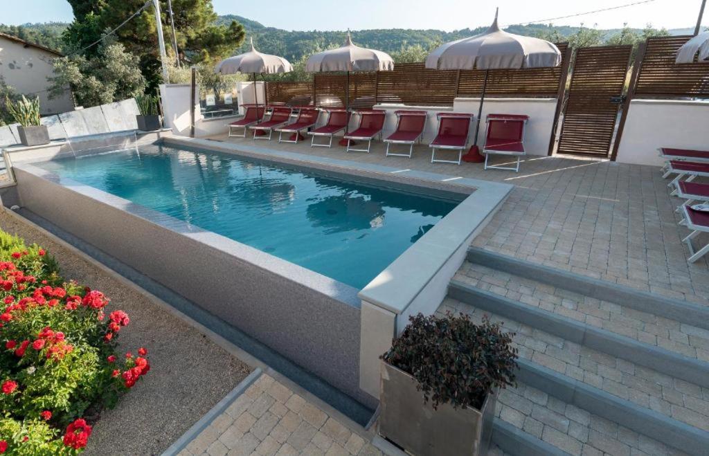 蒙特瓦尔基Dependance Villa Sassolini的一座带桌椅和鲜花的游泳池