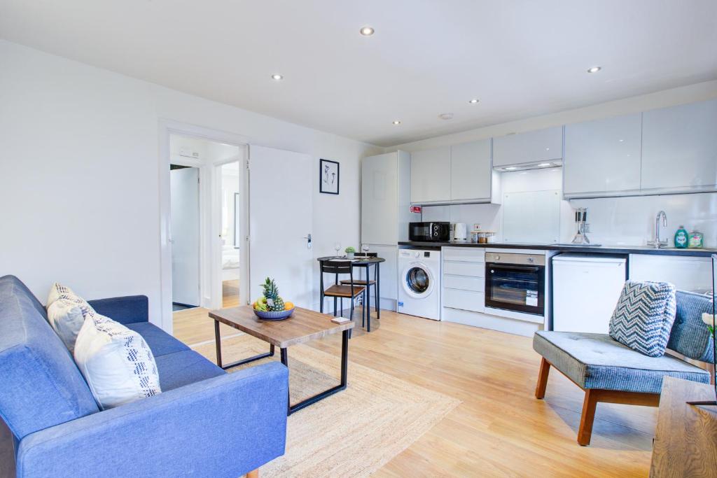 伦敦Wonderful Two-Bedroom Apartment的一间带蓝色沙发的客厅和一间厨房