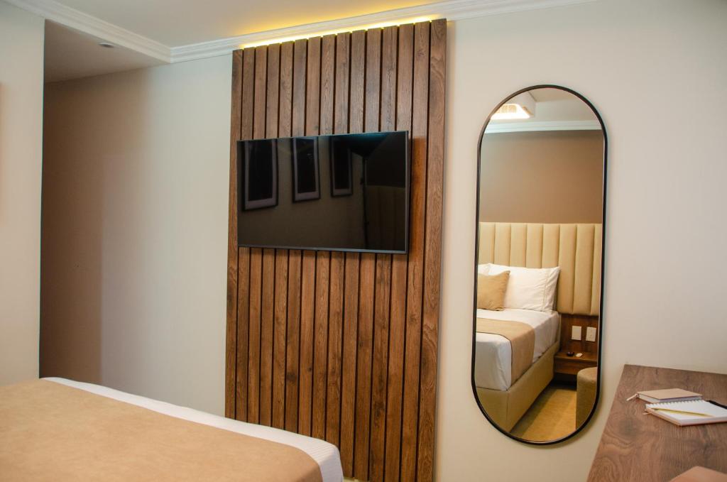 波哥大Hotel ByHours Las Américas的酒店客房带镜子和一张床
