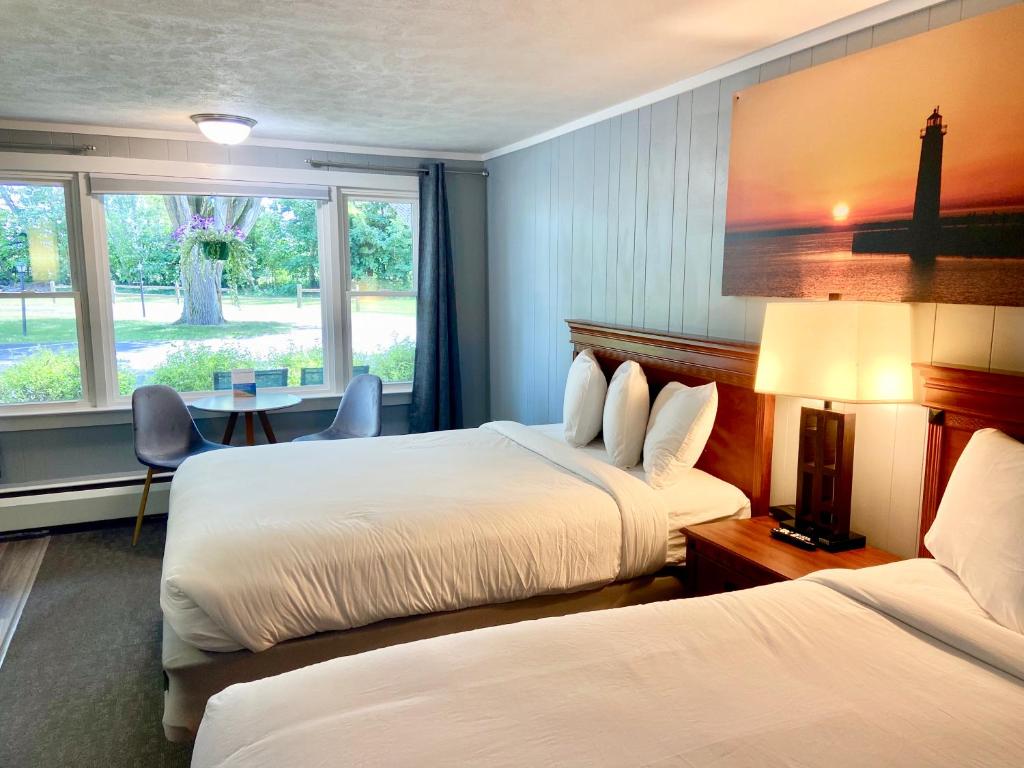 Elk RapidsElk Rapids Lakeshore Inn的酒店客房设有两张床和一张桌子。