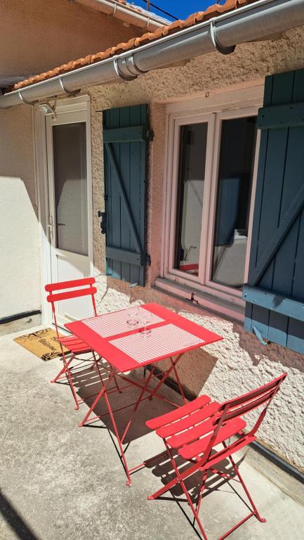 土伦Ancien appartement de pêcheur的大楼前的两把红色椅子和一张桌子