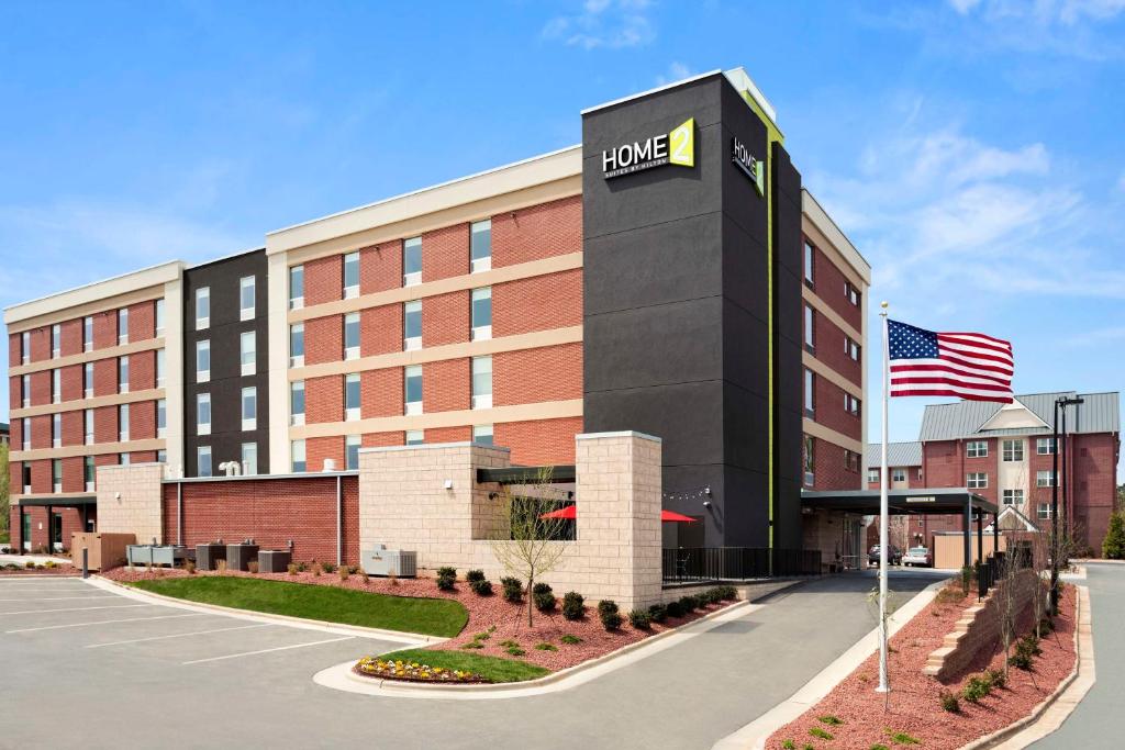 格林斯伯勒Home2 Suites by Hilton Greensboro Airport, NC的前面有美国国旗的酒店大楼