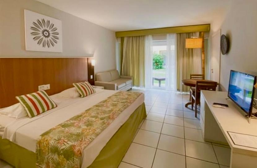 布希奥斯Búzios beach resort的酒店客房配有一张床、一张书桌和一台电视。