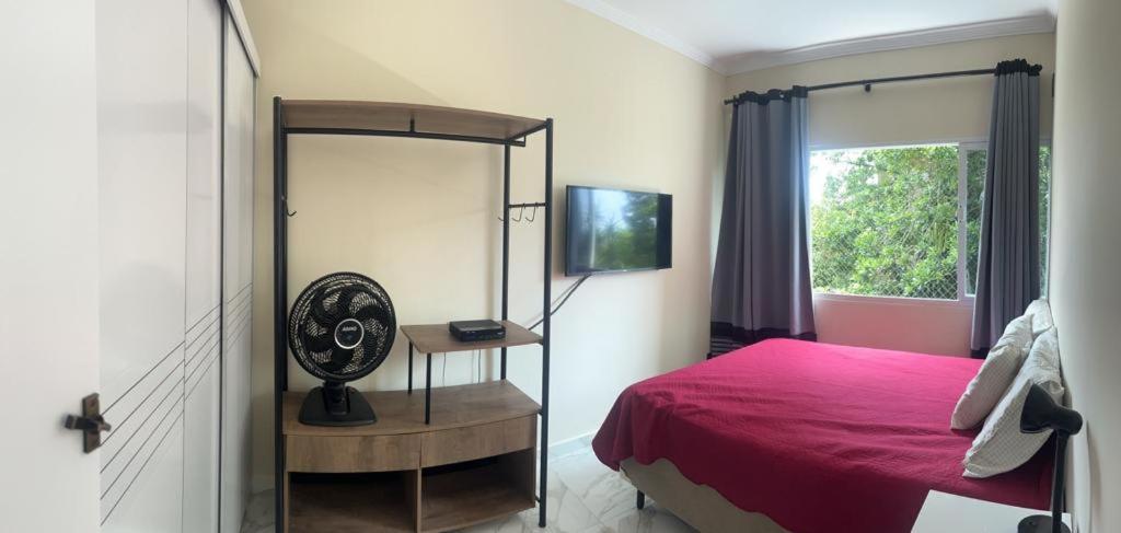 圣维森特岛Apartamento em Ilha Porchat的一间卧室配有红色的床和镜子