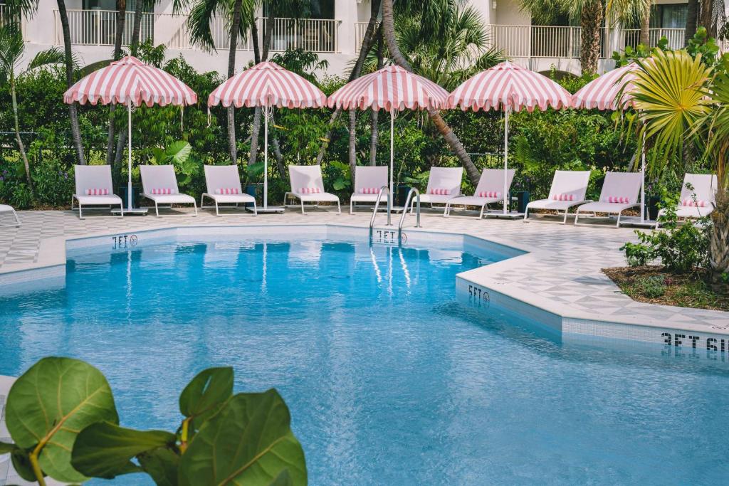 乔治敦Hampton by Hilton Grand Cayman Seven Mile Beach的一个带椅子和遮阳伞的游泳池