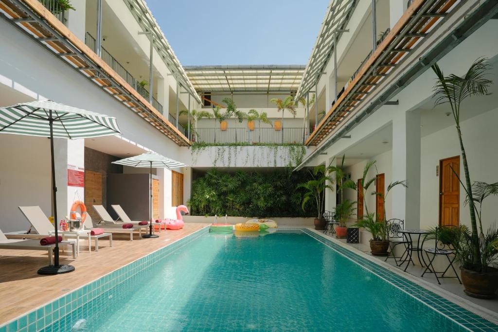 卡塔海滩Nonnee Hotel Kata Beach Phuket的一座带椅子和遮阳伞的游泳池