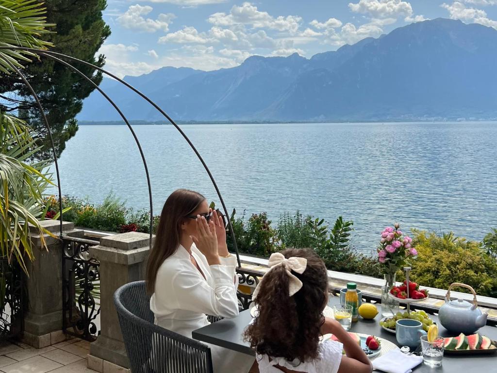 蒙特勒Montreux Luxury Suite的坐在水边桌子上的女人和孩子