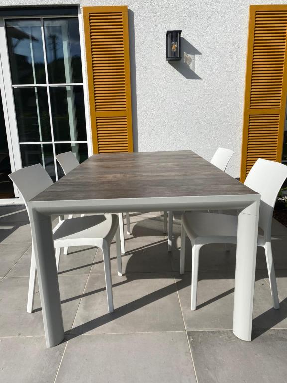 巴特维塞Das Bad Wiessee 22的庭院里设有一张木桌和白色椅子