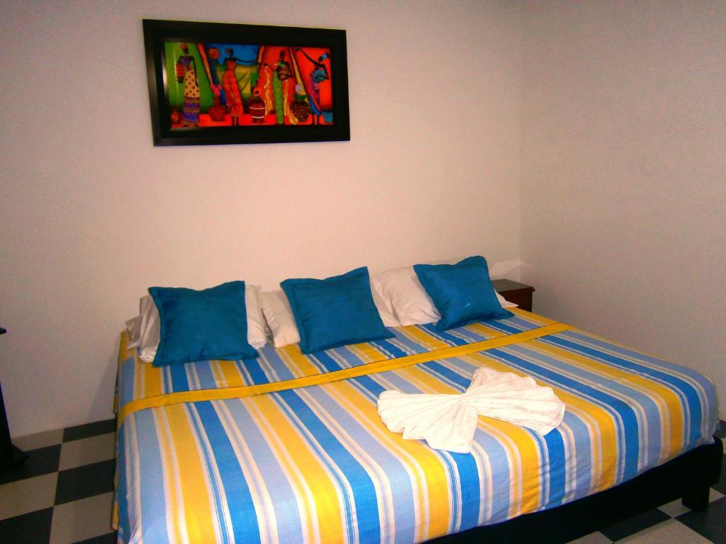 瓜杜阿斯Hotel Shalom PHE Guaduas的一张带蓝色枕头的床和墙上的绘画