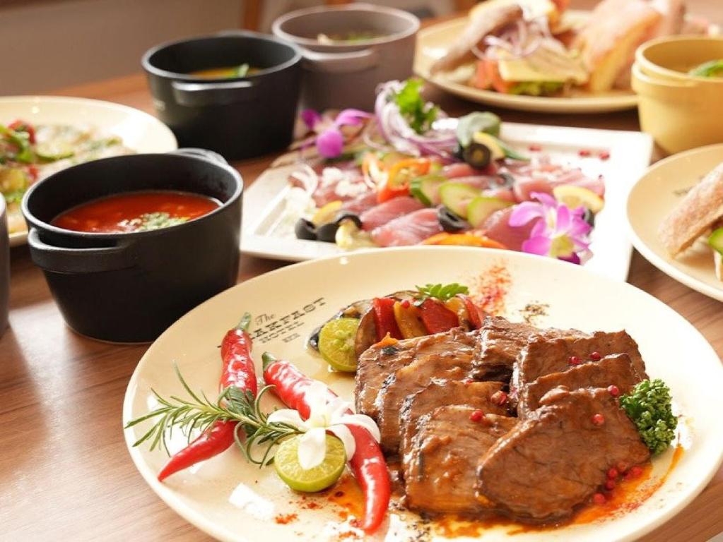 石垣岛The BREAKFAST HOTEL MARCHE Ishigaki Island的餐桌,带肉和蔬菜的盘子