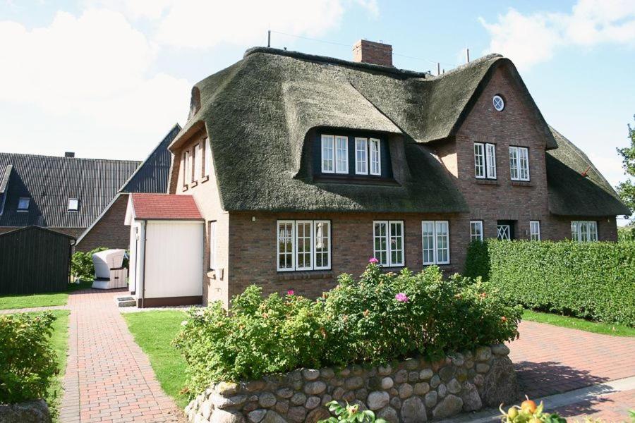 AlkersumHaus Grünland的茅草屋顶和石墙的房子