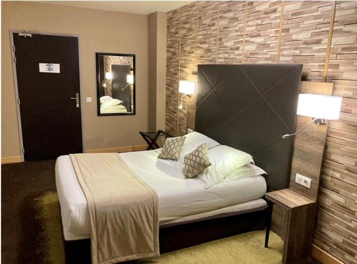 康布雷Logis Hôtel & Restaurant - Le Mouton Blanc的一间卧室设有一张床和砖墙