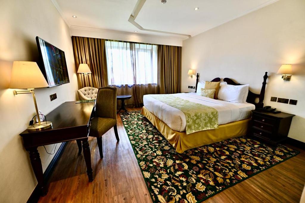 纳库鲁Midland Hotel Nakuru的配有一张床和一张书桌的酒店客房
