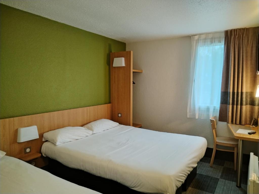 蒙吕松Hotel Inn Design Montluçon的酒店客房设有两张床和窗户。