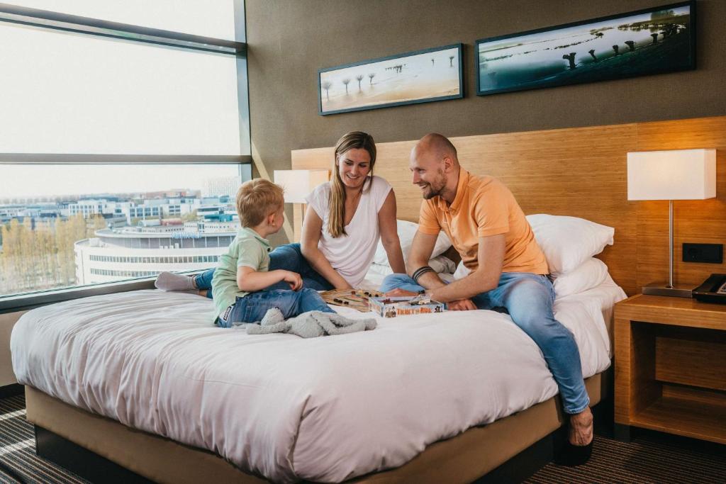 霍夫多普 阿姆斯特丹机场凯悦酒店的坐在酒店房间床边的家庭