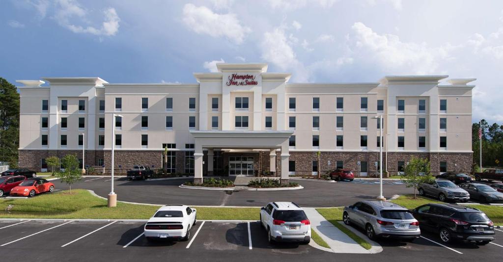费耶特维尔Hampton Inn and Suites Fayetteville, NC的一座白色的大建筑,汽车停在停车场