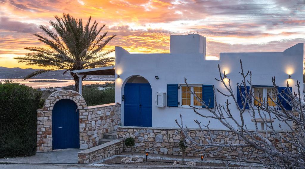 Nea Cryssi AktiNoho Villas @ Sunlit house Paros的白色的房子,有蓝色的门和棕榈树