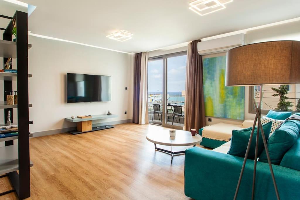 海若克利欧Minimal Loft Art with Sea View Over Heraklion Harbour的客厅配有蓝色的沙发和电视