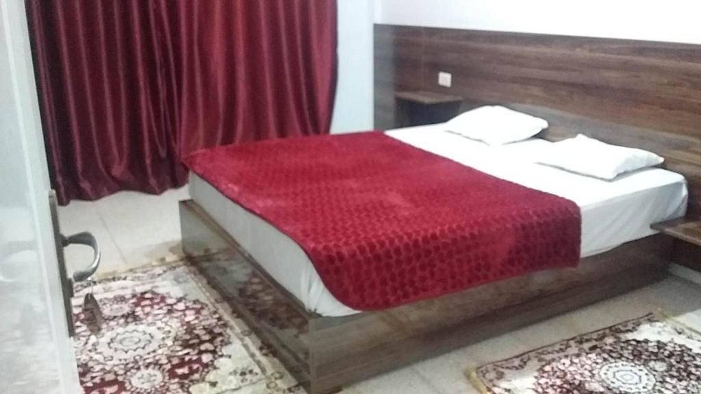 泰塔温hotel amilcar tataouine的一间卧室配有一张带红色毯子的床