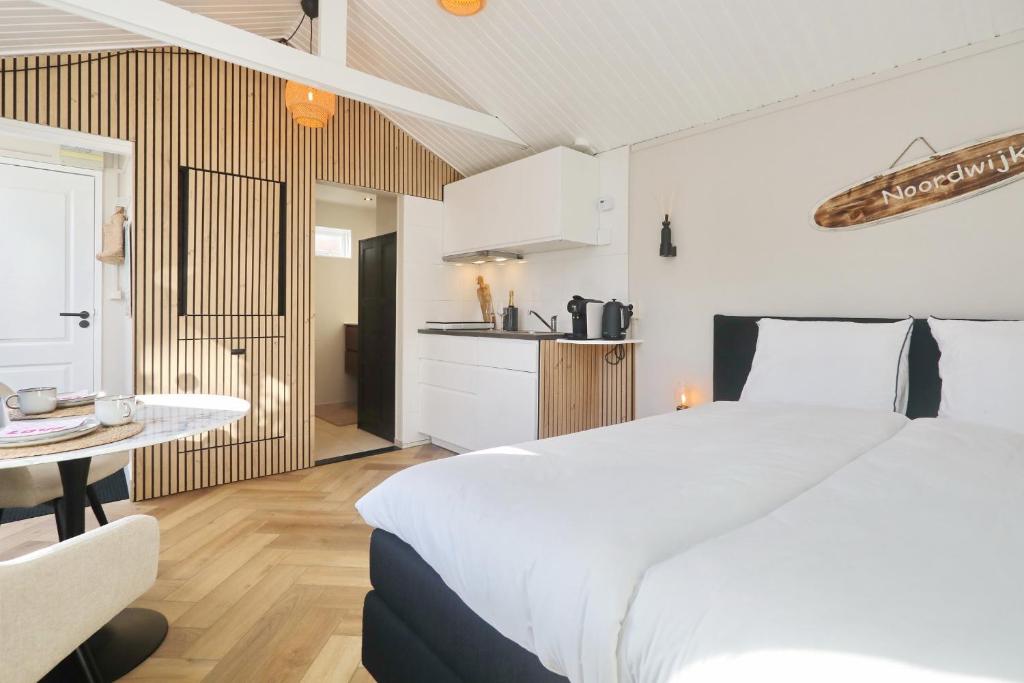 海滨诺德韦克Huisje bij Zee (gratis parkeren)的一间带白色大床的卧室和一间厨房