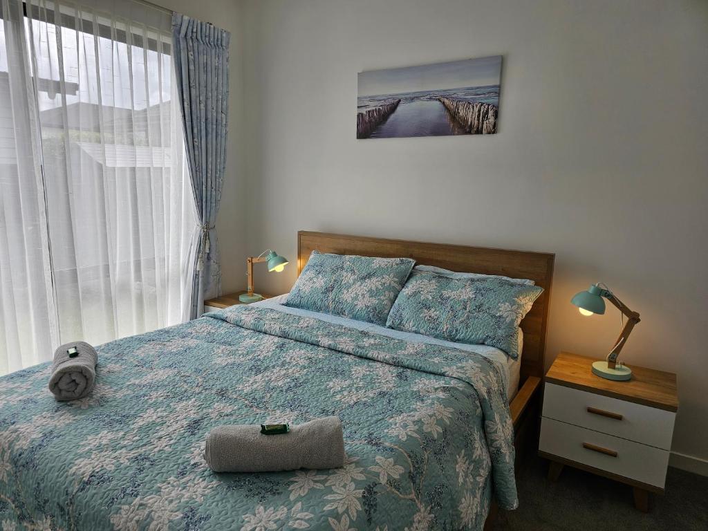SilverdaleTui Nest Garden Unit的一间卧室配有一张带蓝色棉被的床