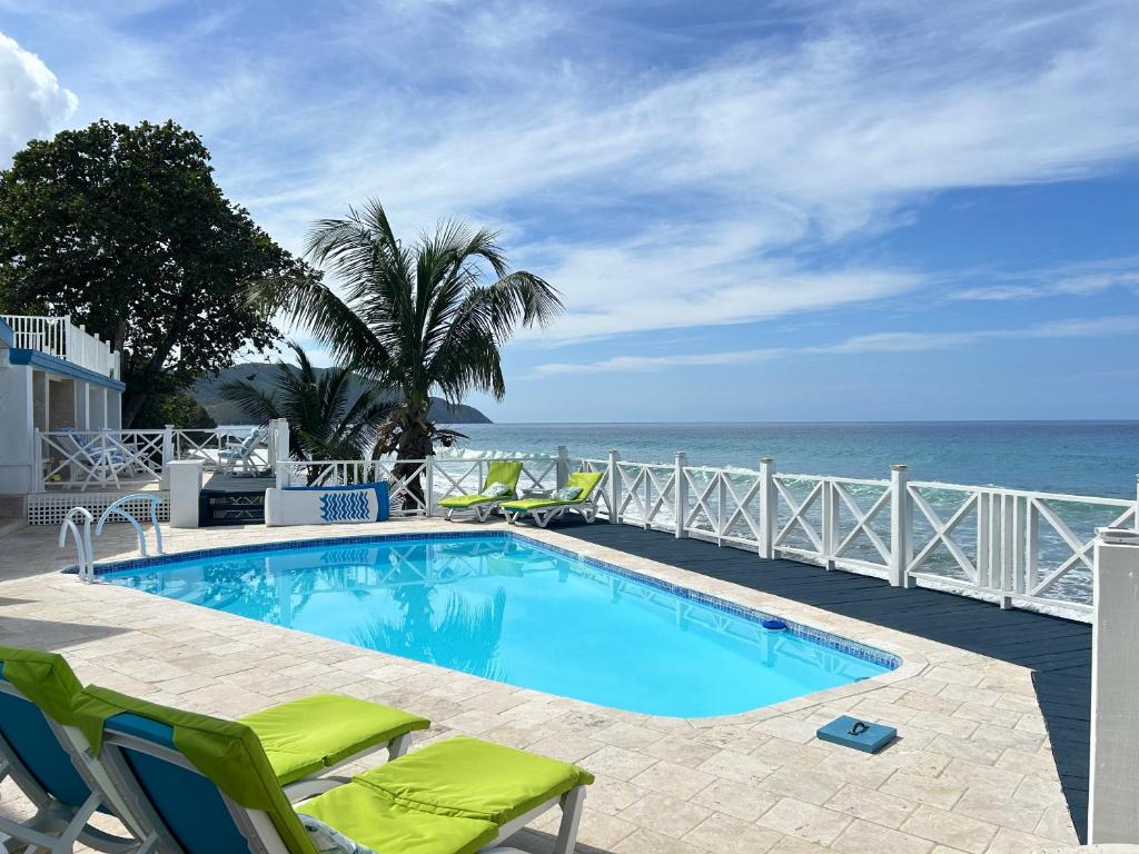 FrederikstedNorth Star Villa Oceanfront Family-Retreat With Pool的一个带椅子的游泳池,背景是大海