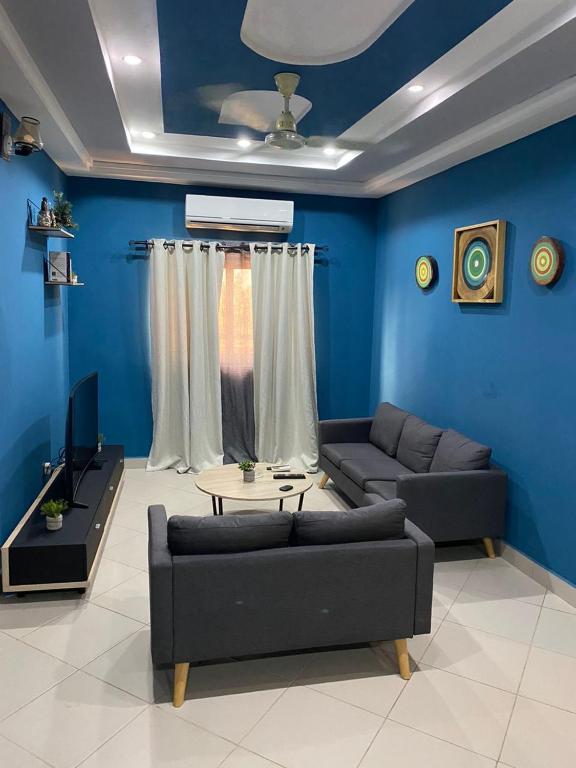 Abomey-CalaviAGENCE IMMOBILIÈRE GDS BENIN的客厅设有蓝色的墙壁、一张沙发和一张桌子