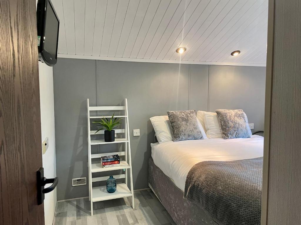 南塞尔尼Cosy 3 Bed Lodge in Hoburne, Cotswolds的卧室配有床和白色架子