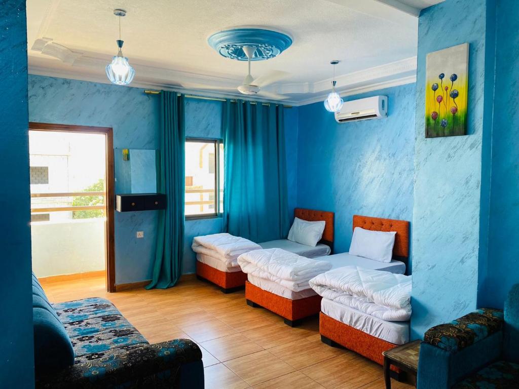 亚喀巴Galaxy Apartments的蓝色的客房配有两张床和一张沙发