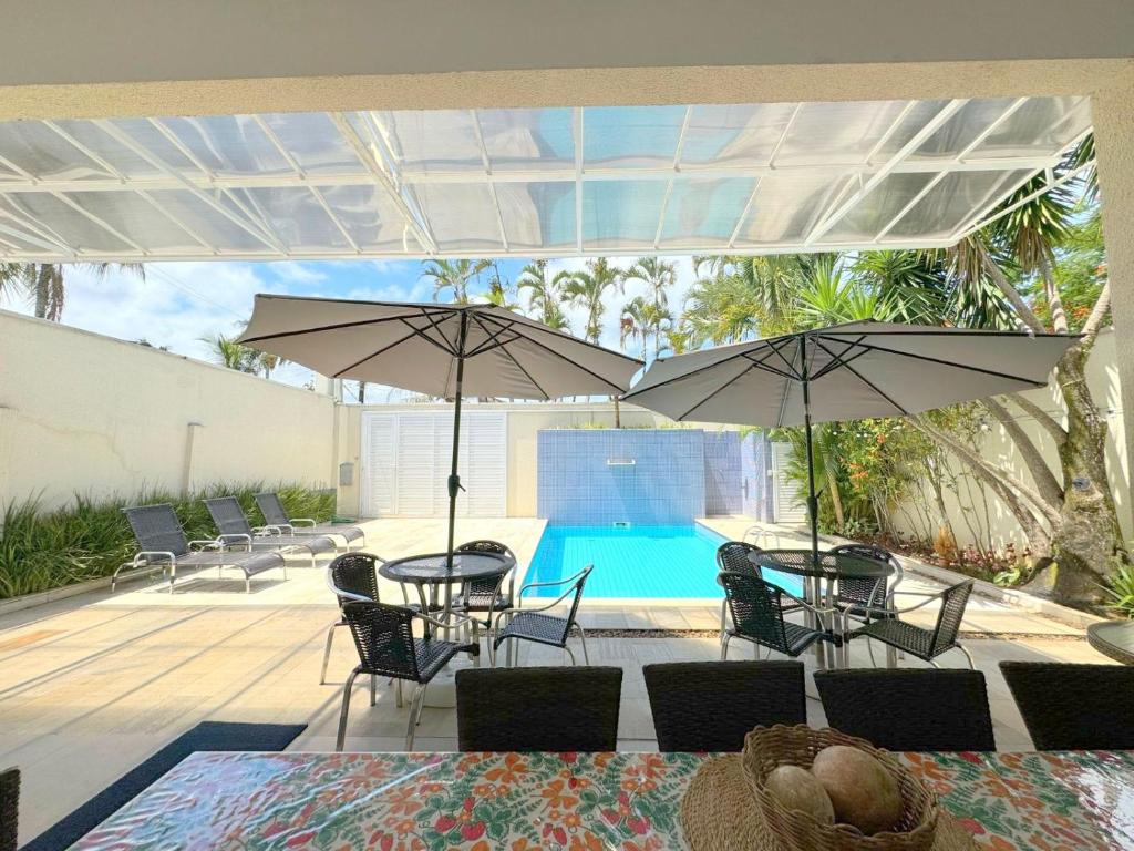 瓜鲁雅Pousada Village Cozumel的一个带桌子和遮阳伞的庭院和一个游泳池
