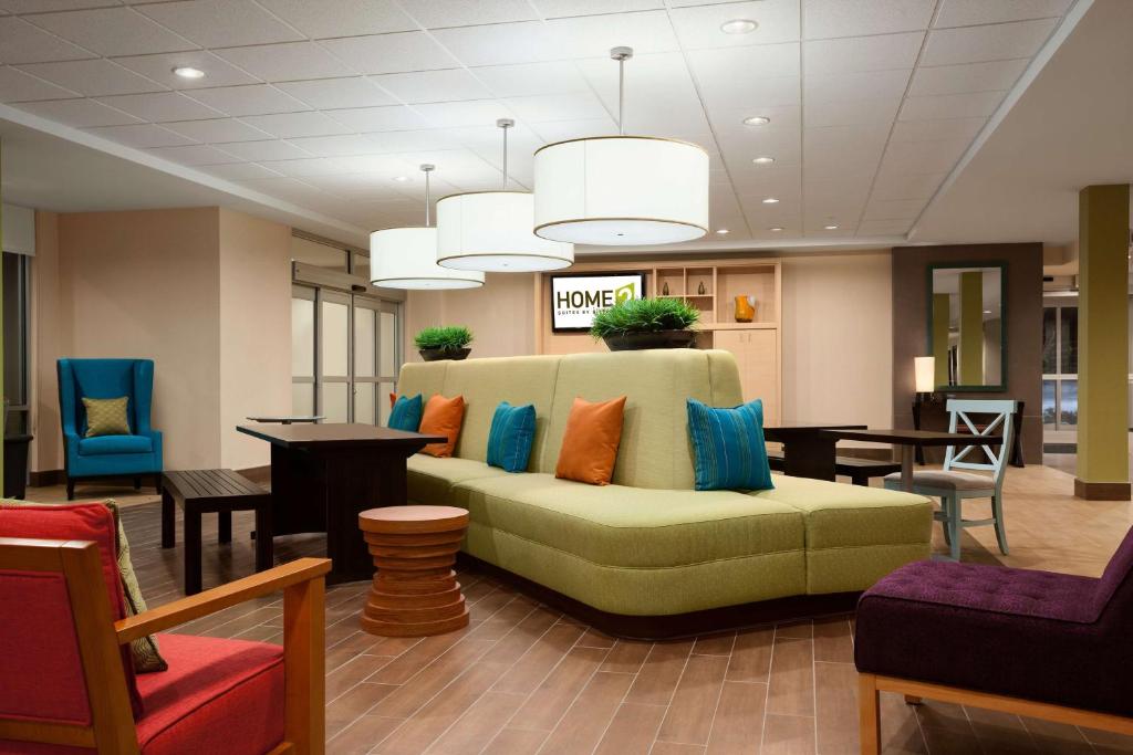 拉威拉威希尔顿欣庭套房酒店的大堂设有绿沙发,配有色彩缤纷的枕头