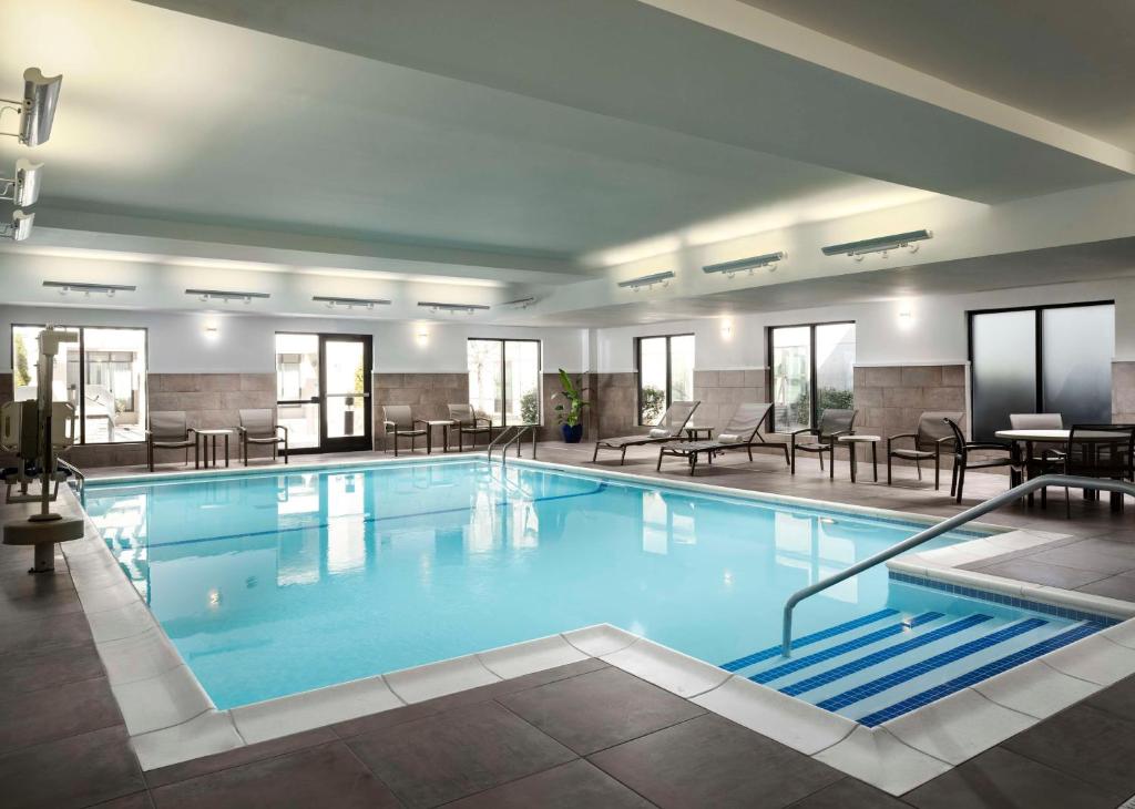 Carle PlaceHomewood Suites by Hilton Carle Place - Garden City, NY的酒店的大型游泳池配有桌椅
