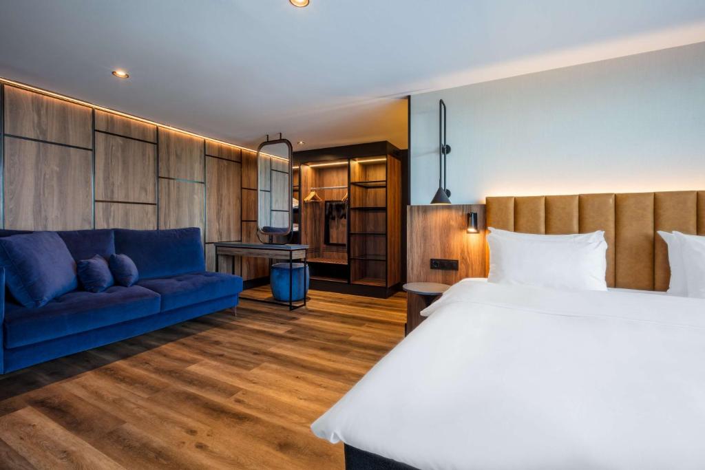 特隆赫姆特隆赫姆皇家花园丽笙酒店的一间卧室配有一张大床和一张蓝色的沙发