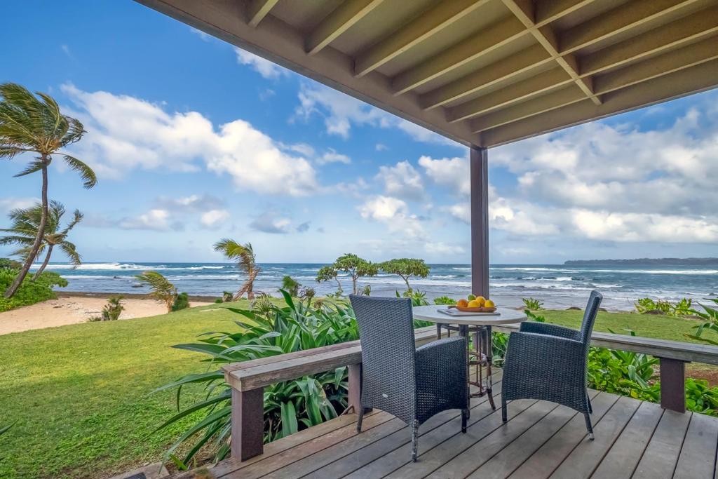 哈纳莱伊Hanalei Colony Resort I-1的一个带桌椅的甲板和大海