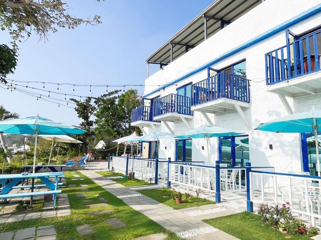南湾黃金海岸36海景旅店的前面有蓝色桌子和遮阳伞的建筑