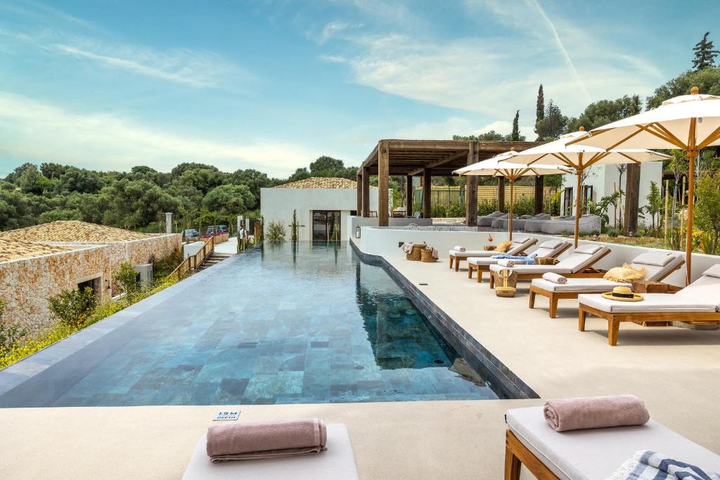 斯巴达Eliamos Villas Hotel & Spa的别墅内设有带躺椅和遮阳伞的无边泳池