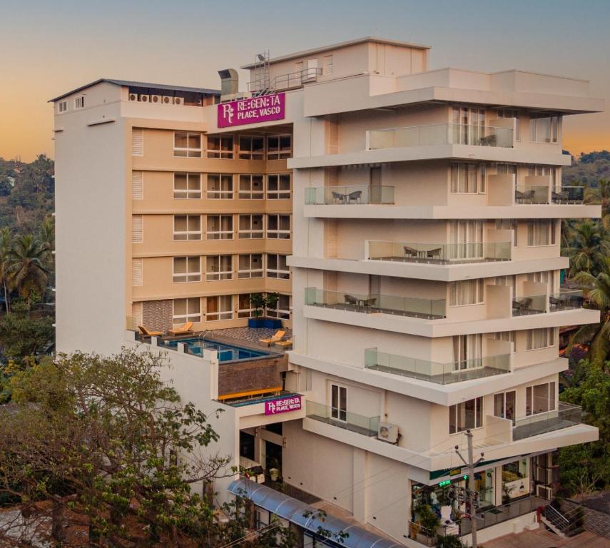莫尔穆冈Regenta Place Vasco Goa的一座高大的白色建筑,设有阳台