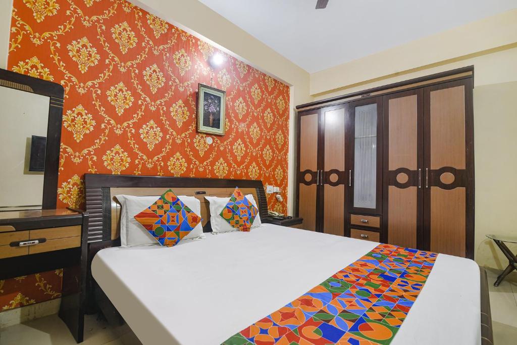 巴特那FabHotel Maadhavam Residence的一间卧室设有一张床和橙色的墙壁