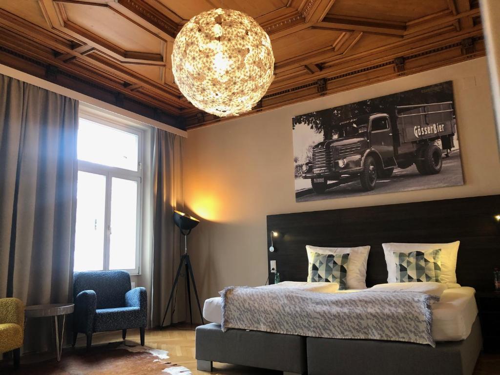 维也纳Hotel Brauhof Wien的一间卧室配有一张大床和一个吊灯。