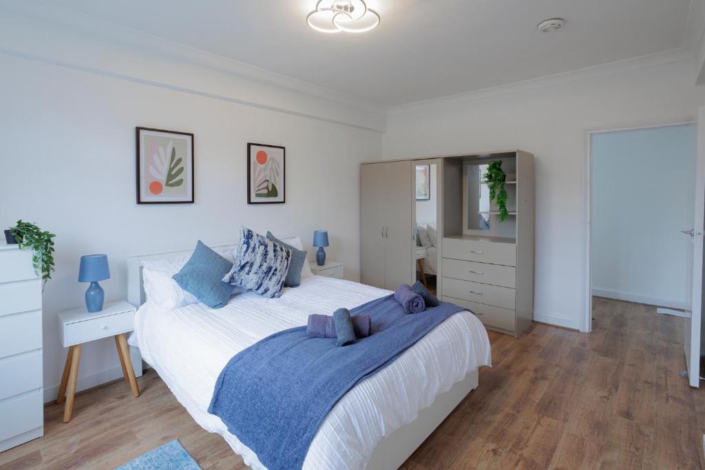 伦敦Lovely 2-bed Highbury Home的白色卧室配有一张带蓝色枕头的大床